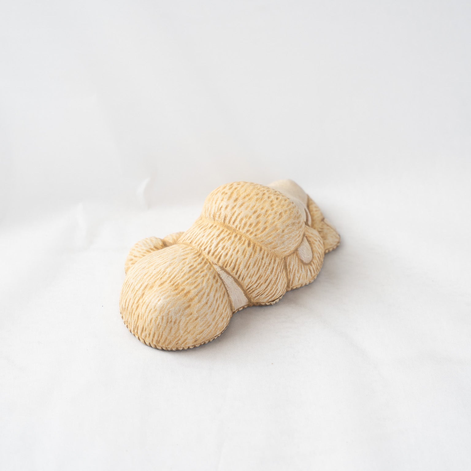 High-angle view from behind the curled sleeping poodle leather object, emphasizing the smooth transitions of the three-dimensionally molded leather shape.
