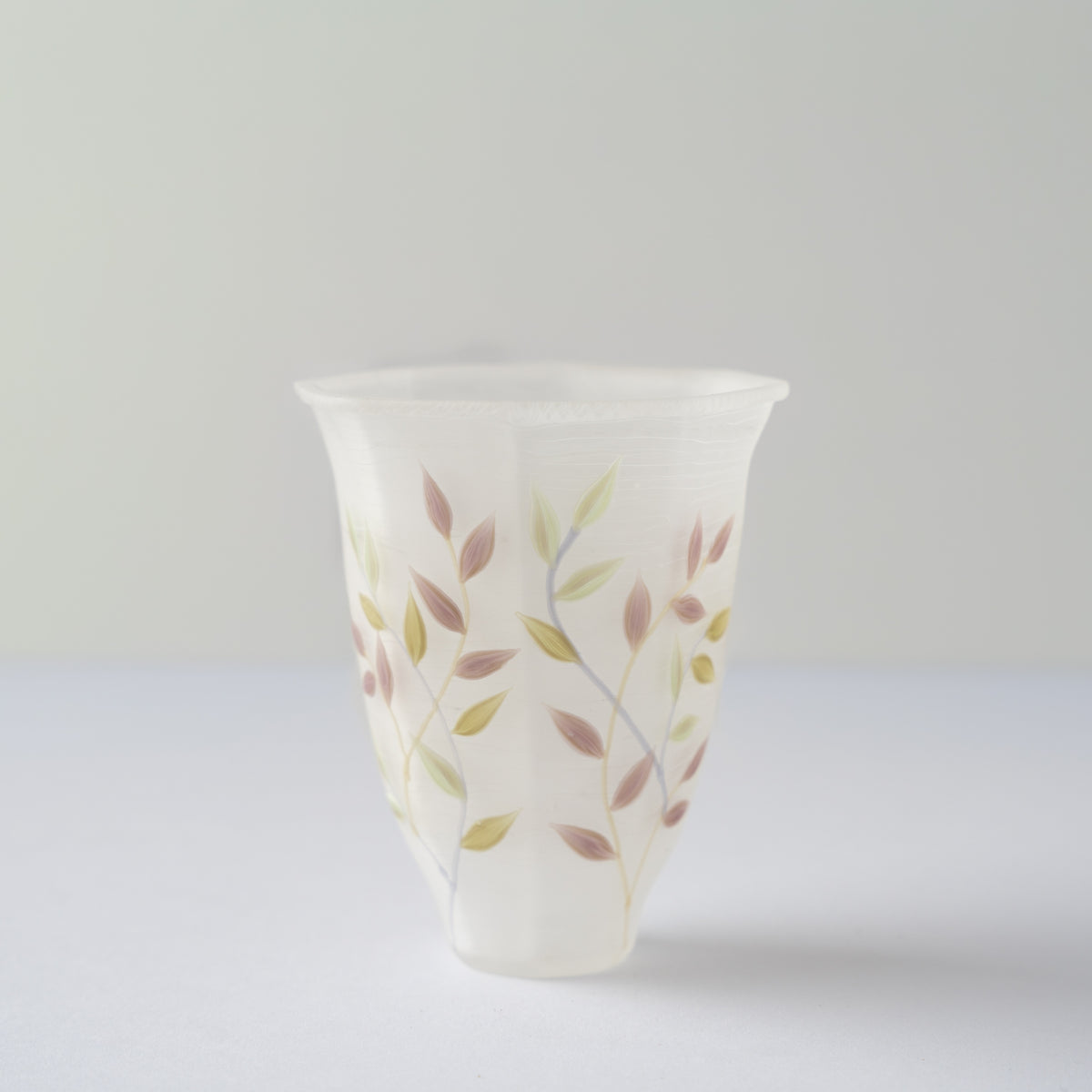 Side profile of Toru Sato’s white octagonal glass GUINOMI, showcasing the subtle green and dusky pink karakusa leaf brushwork.