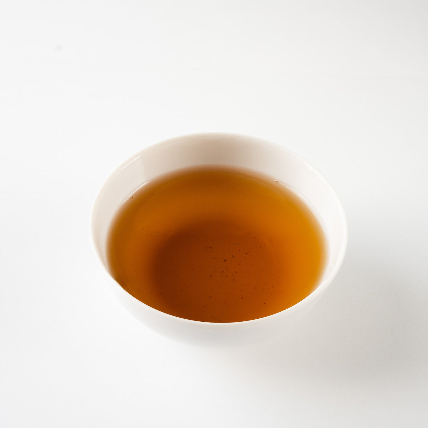 White porcelain cup filled with freshly brewed hojicha, showcasing its deep amber depth and quiet presence.