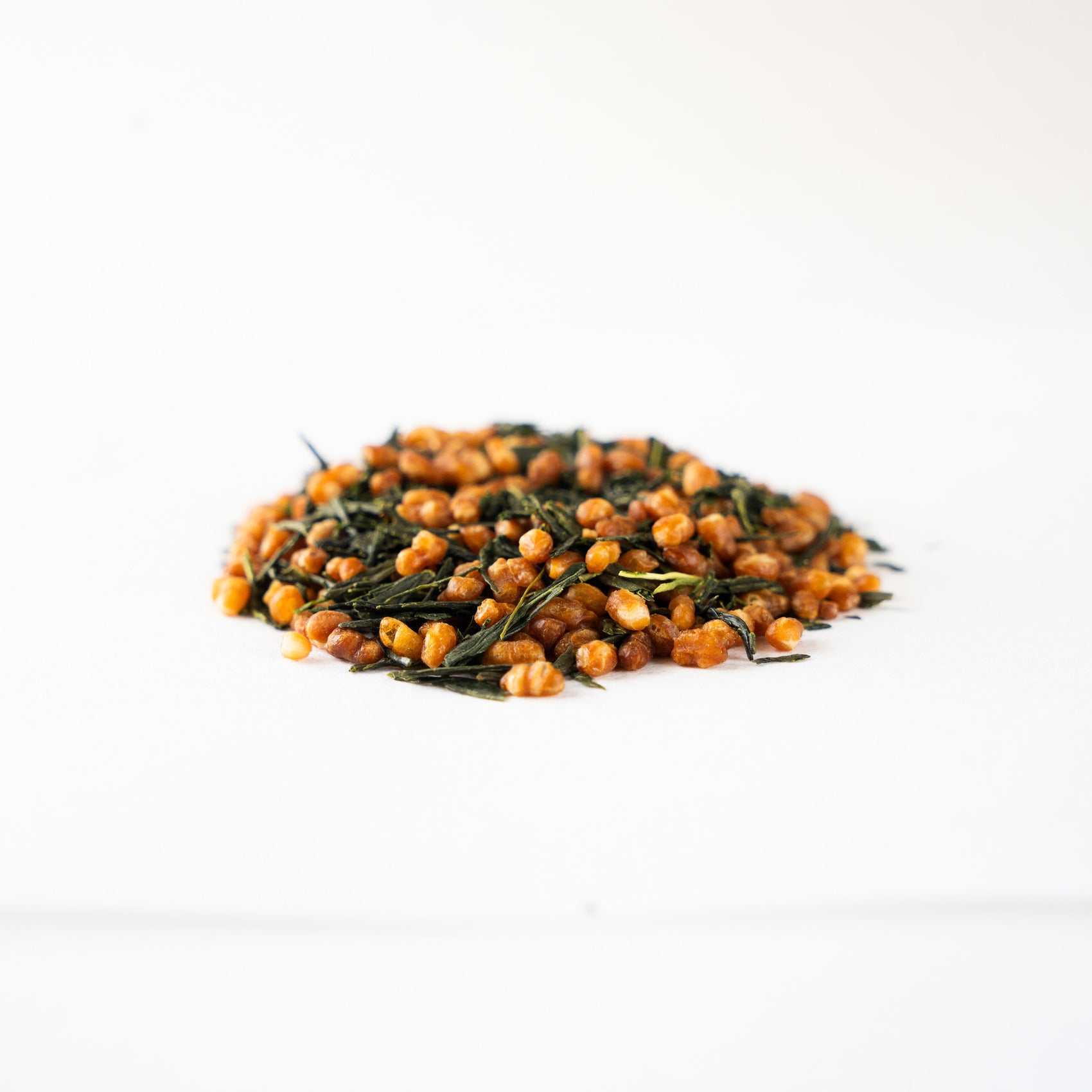 Close-up side view of premium Genmaicha tea showing roasted Milky Queen rice and green tea leaves, capturing the comforting toasted aroma found in Hojicha.