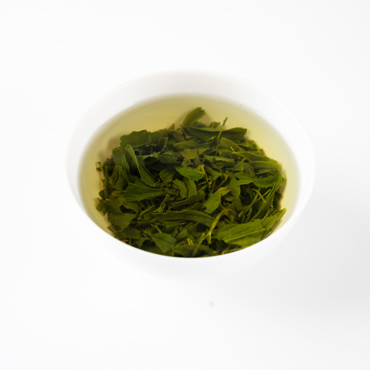 Les feuilles du sencha « Nonokaze » s’épanouissent dans l’eau chaude, au creux d’un bol de porcelaine blanche.