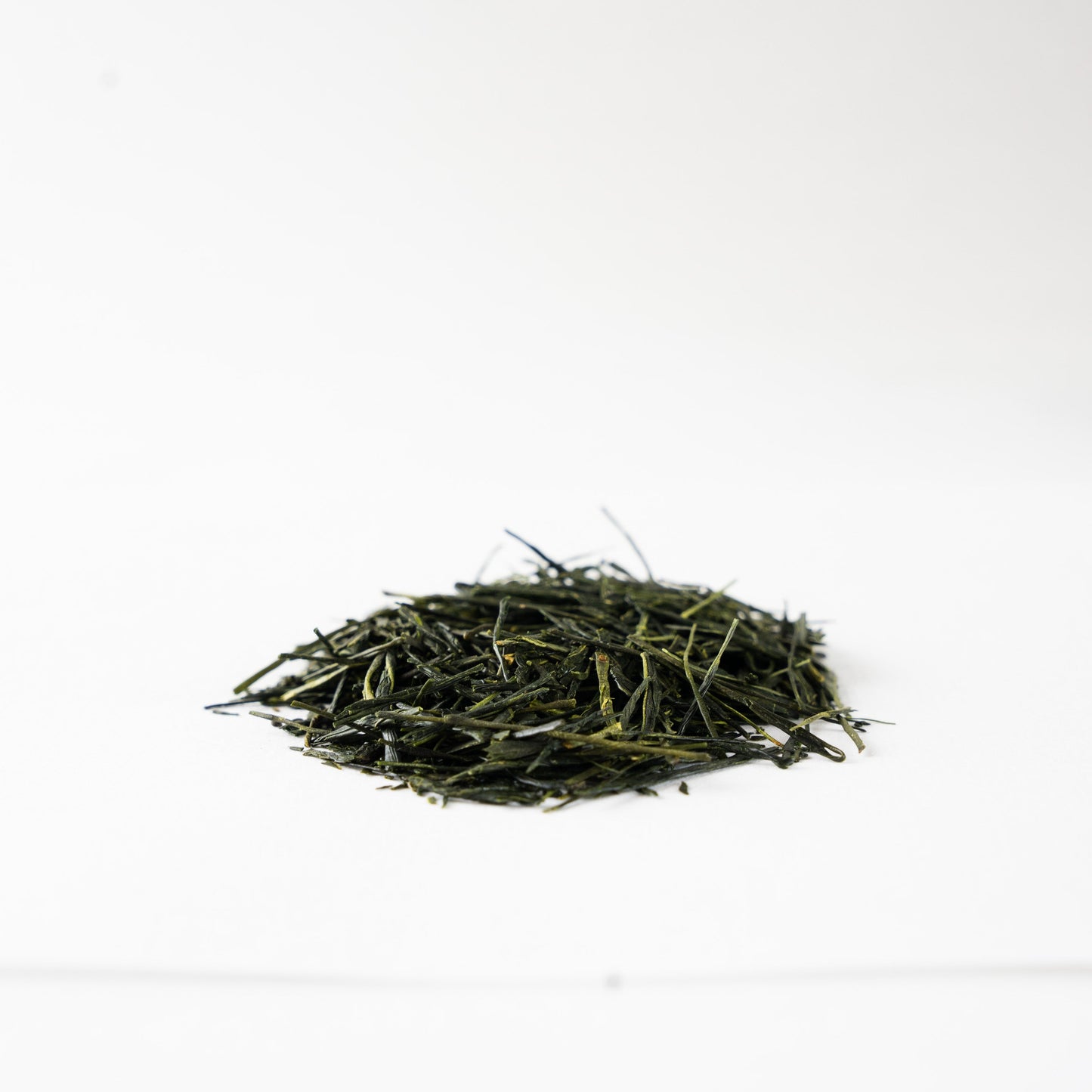 Close-up profile view of glossy, tightly rolled Sencha green tea leaves 'Nonokaze', showcasing fine artisanal quality.