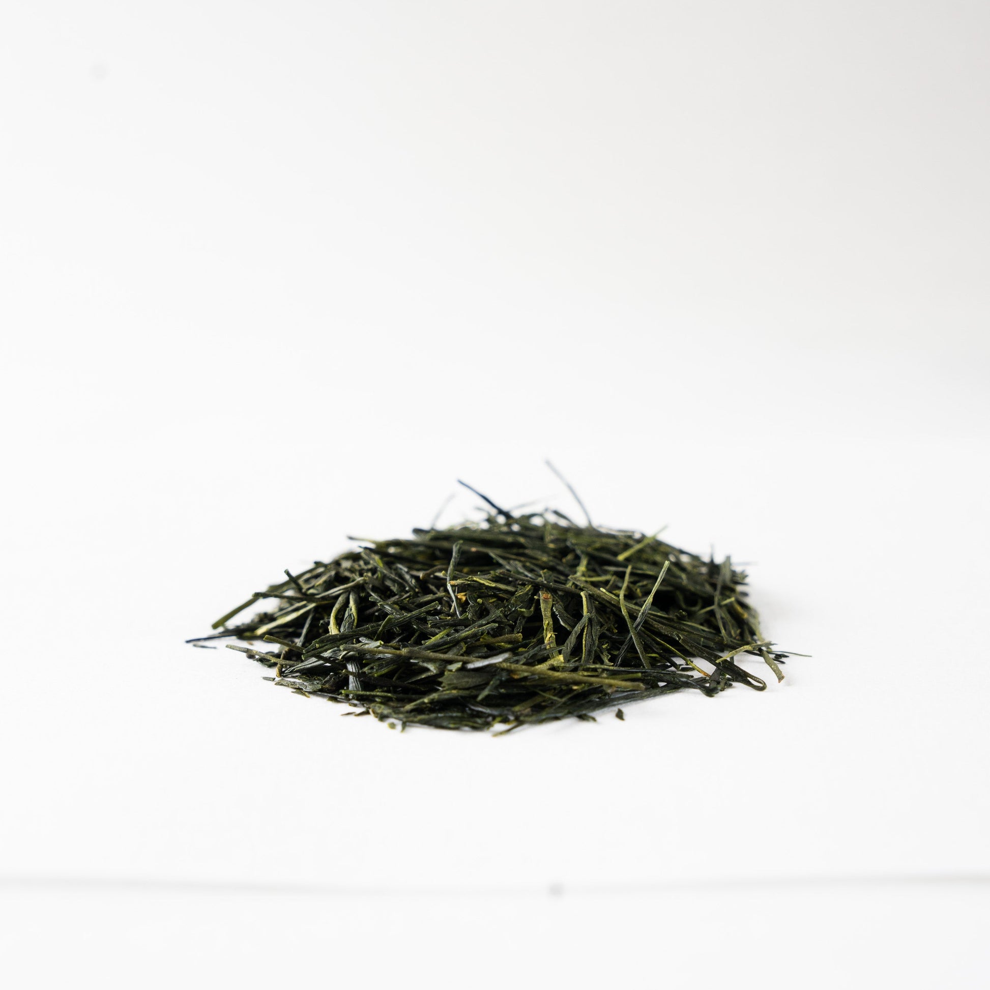 Close-up profile view of glossy, tightly rolled Sencha green tea leaves 'Nonokaze', showcasing fine artisanal quality.