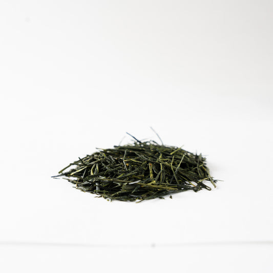 Close-up profile view of glossy, tightly rolled Sencha green tea leaves 'Nonokaze', showcasing fine artisanal quality.