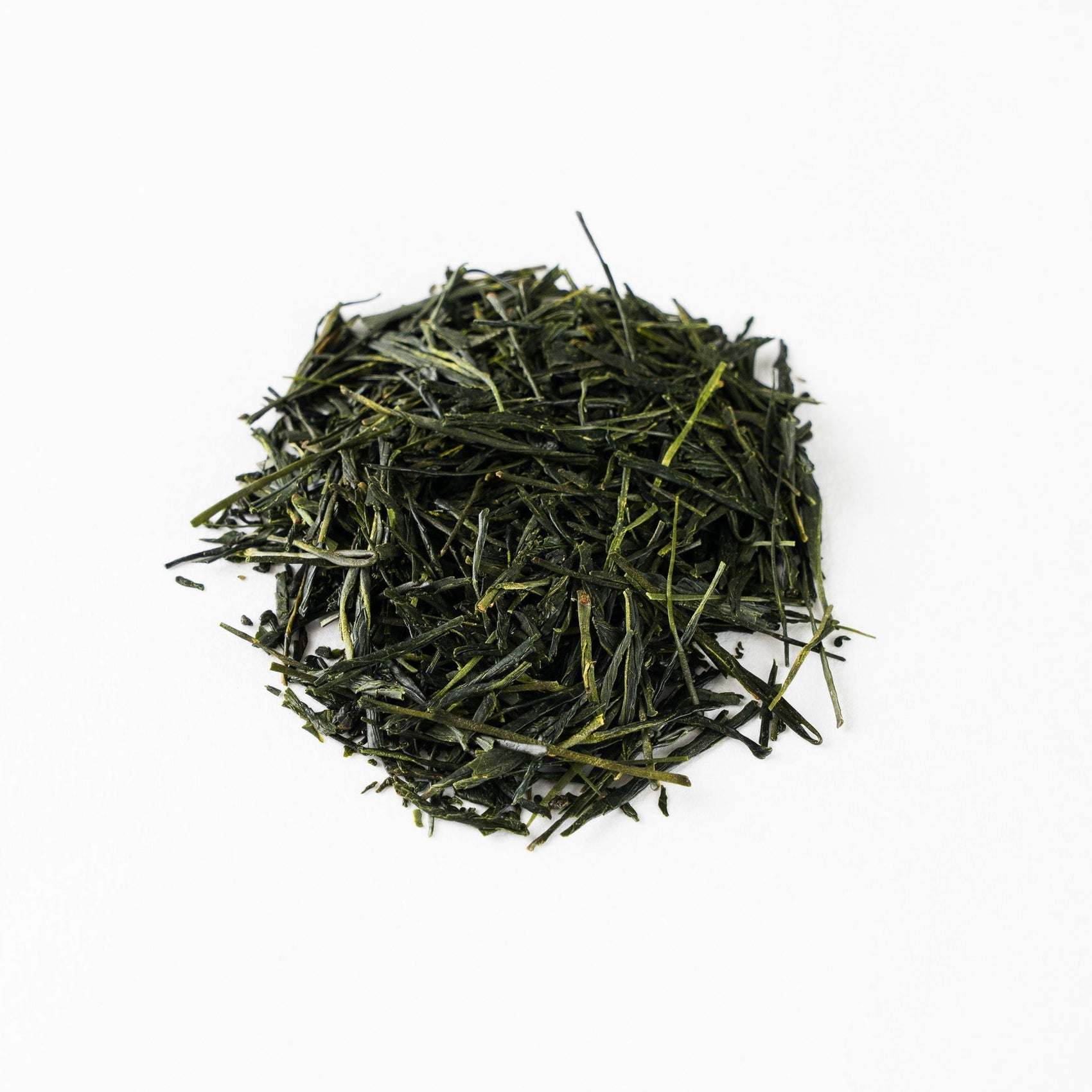 verhead view of premium Japanese Sencha tea leaves 'Nonokaze', featuring dark green needle-like shapes on a clean white background.