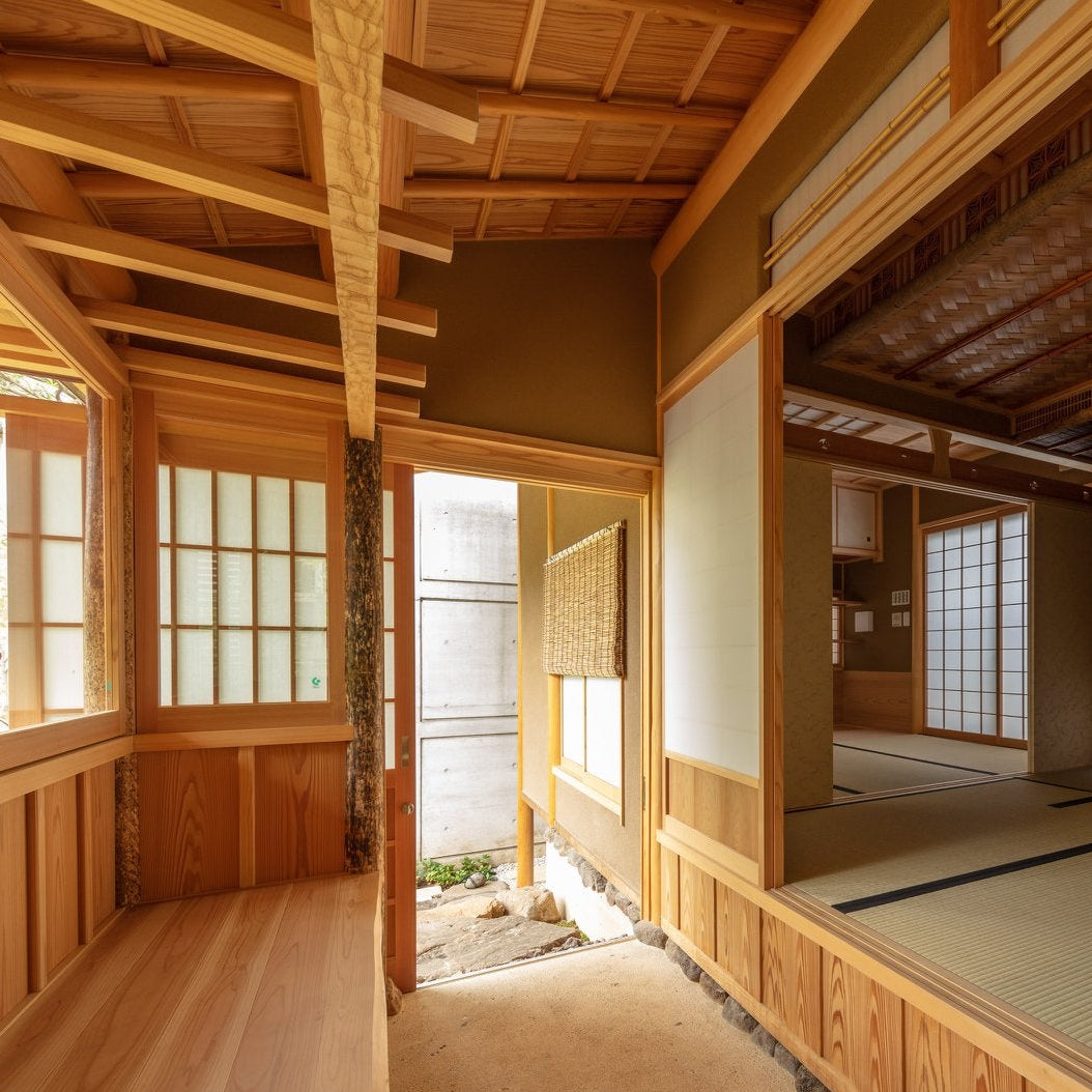 Intérieur d’une salle de thé de style sukiya : poteaux à l’écorce conservée, encadrements de cèdre, murs de terre appliqués à la main, tatami surélevé et shoji.