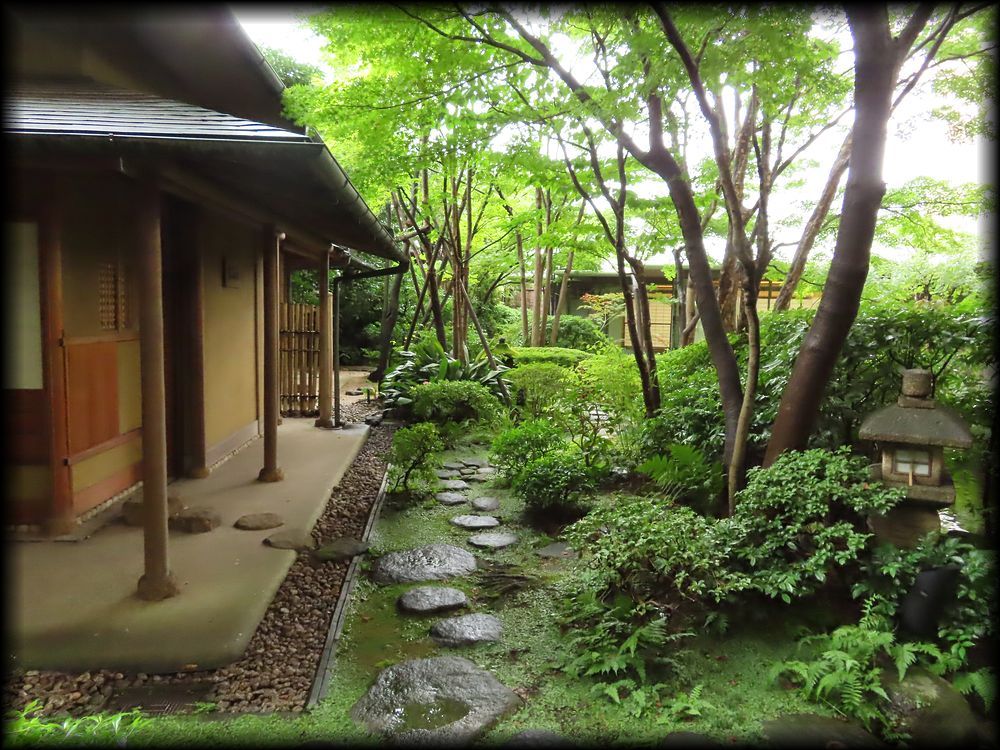 Stepping stones curve through a lush, moss-covered roji garden toward a quiet sukiya-style tearoom, surrounded by vibrant maple leaves and stone lanterns.