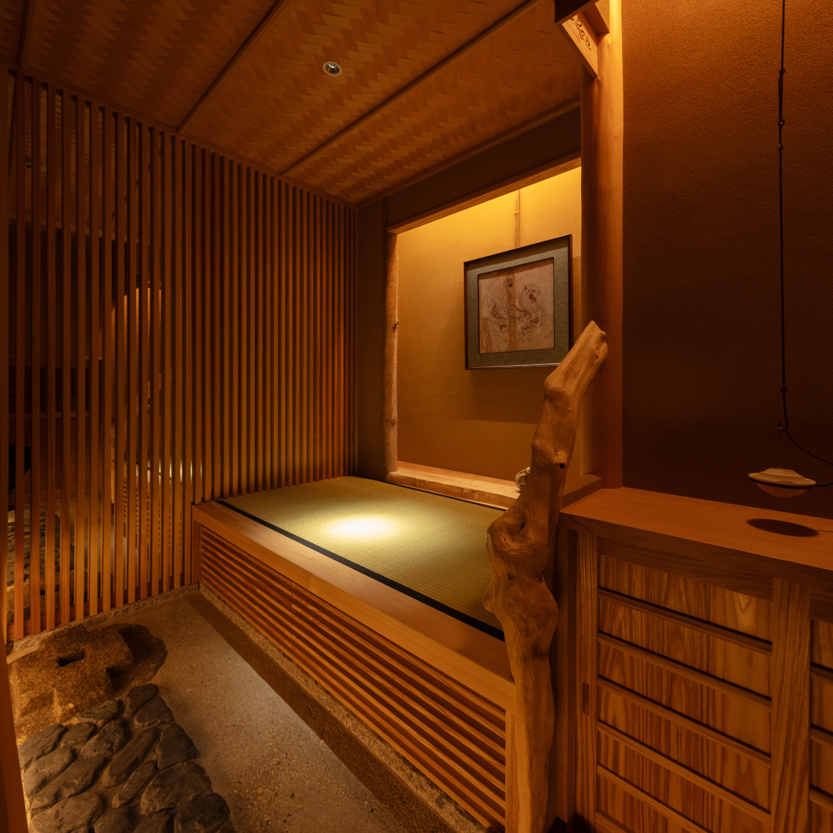 Soft ambient light highlights a raised tatami platform, framed by delicate wooden lattice screens and a raw wood pillar within a serene, contemporary tea space.