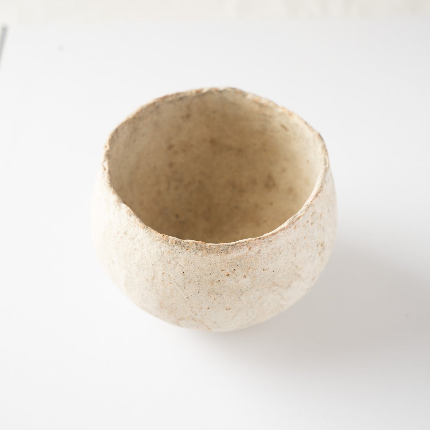 High-angle view of the Bao small ceramic tea bowl by Wataru Myosyu, emphasizing its inward-curving rim and nesting shape.