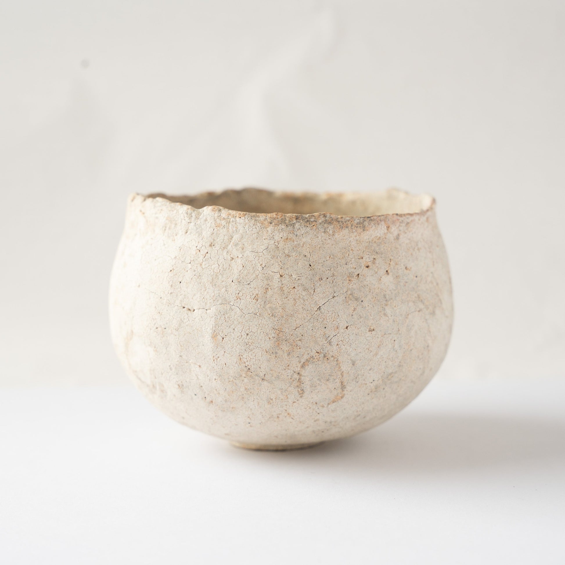 Side view of Wataru Myosyu's Bao small CHAWAN tea bowl, showing its rounded cradled form and chalky white crackle texture.