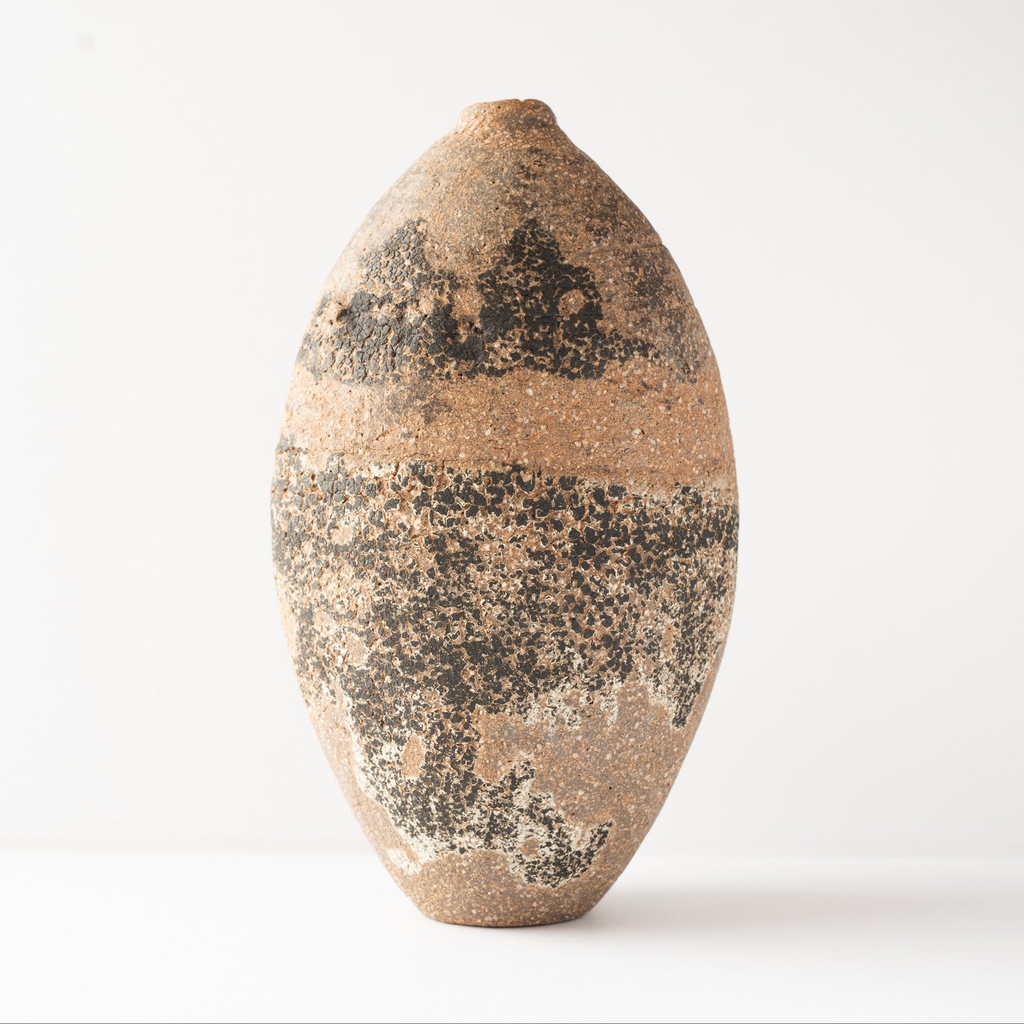 Front studio profile of Wataru Myosyu’s Genkoku ceramic flower vase, highlighting the balanced oval silhouette and rich dark texturing.