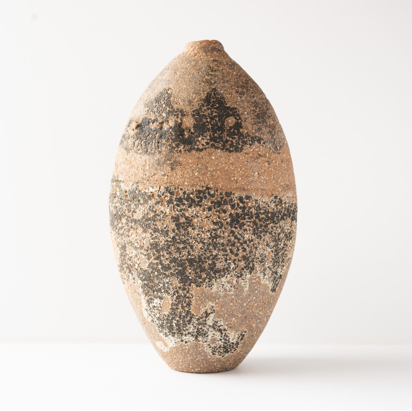 Front studio profile of Wataru Myosyu’s Genkoku ceramic flower vase, highlighting the balanced oval silhouette and rich dark texturing.