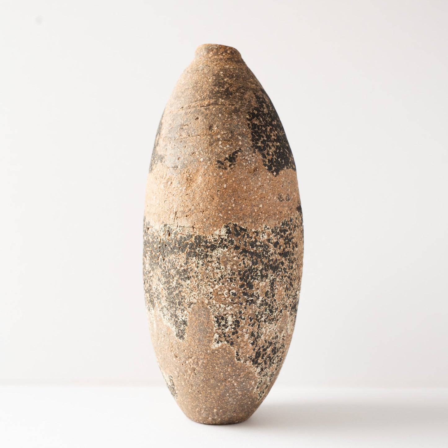 Side view of the Genkoku HANAIRE ceramic vase by Wataru Myosyu, displaying its slender profile and raw, unglazed clay finish.