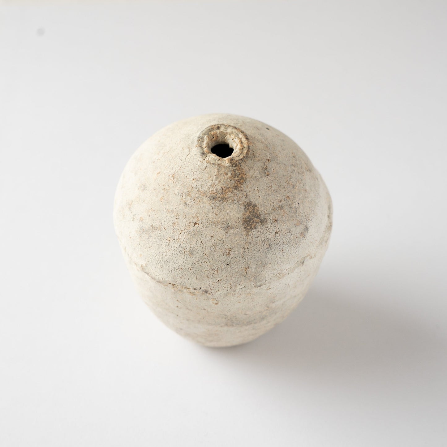 High-angle view looking down at the narrow rim and rounded shoulder of Wataru Myosyu’s Hakkoku Ko white ceramic vase.