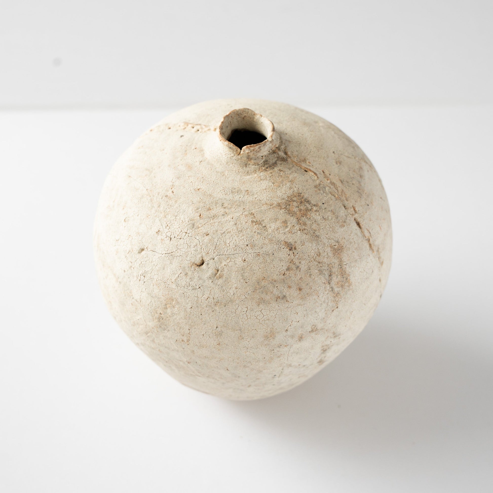High-angle view of Wataru Myosyu's Hakkoku Tada HANAIRE ceramic vase, showing its rounded form and chalky white crackle surface.