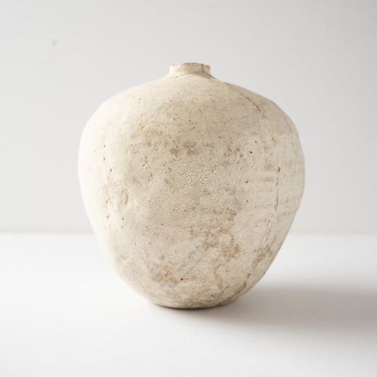 Eye-level side profile of Wataru Myosyu's Hakkoku Tada ceramic flower vase, highlighting the fruit-like spherical silhouette and chalky texture.