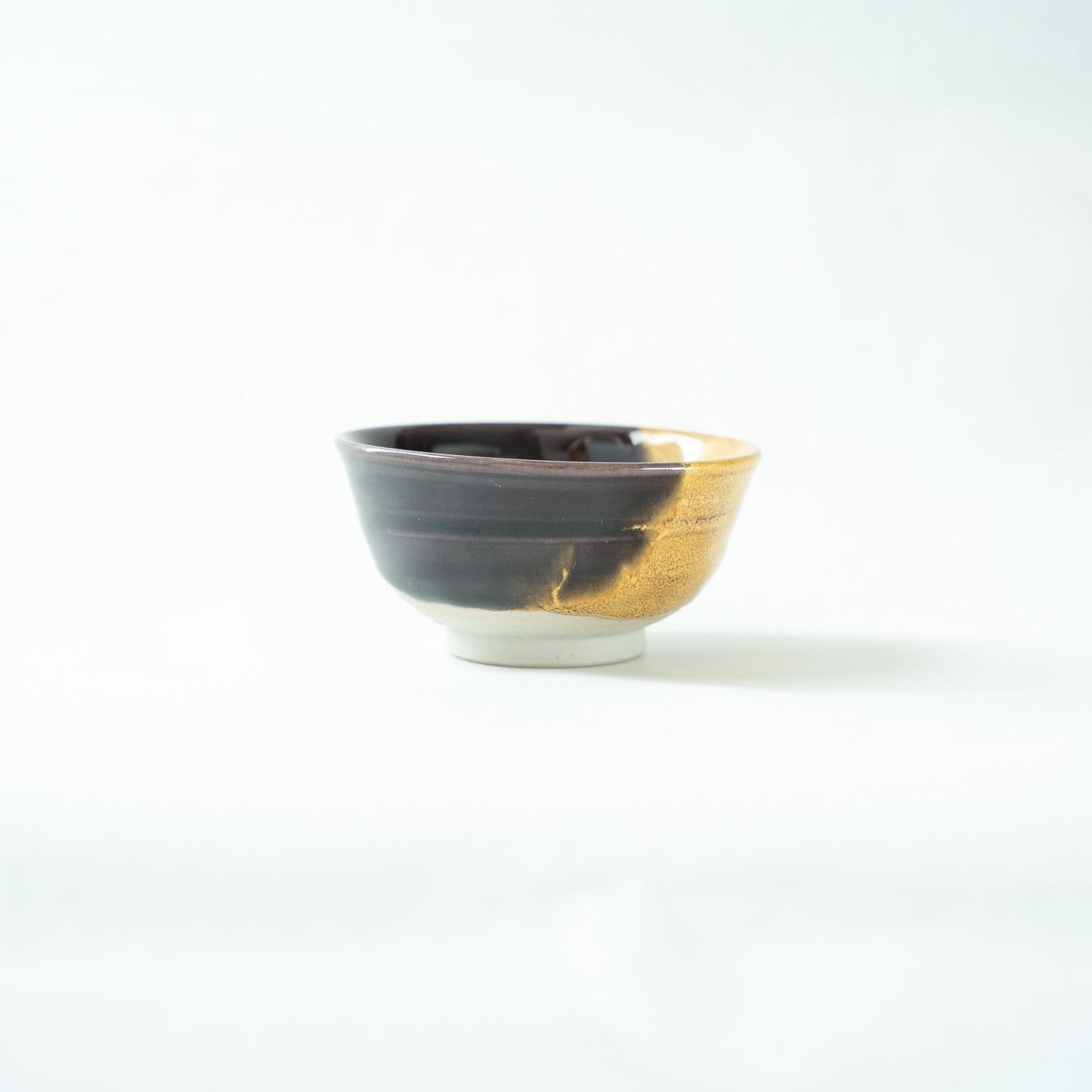 Profile view focusing on the lustrous black glazed side, capturing its deep, calm, and reflective surface.