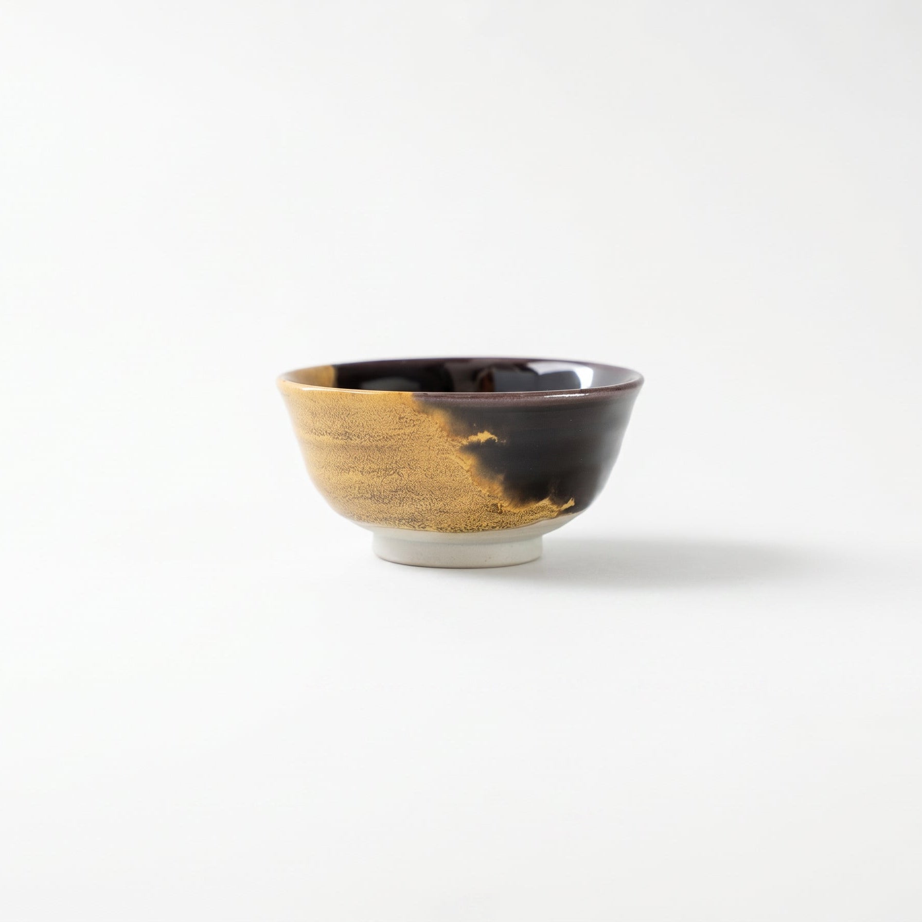 Front view of the Kutani GUINOMI by Tokuda Yasokichi III, showcasing the bold asymmetrical boundary where black and gold glazes meet.