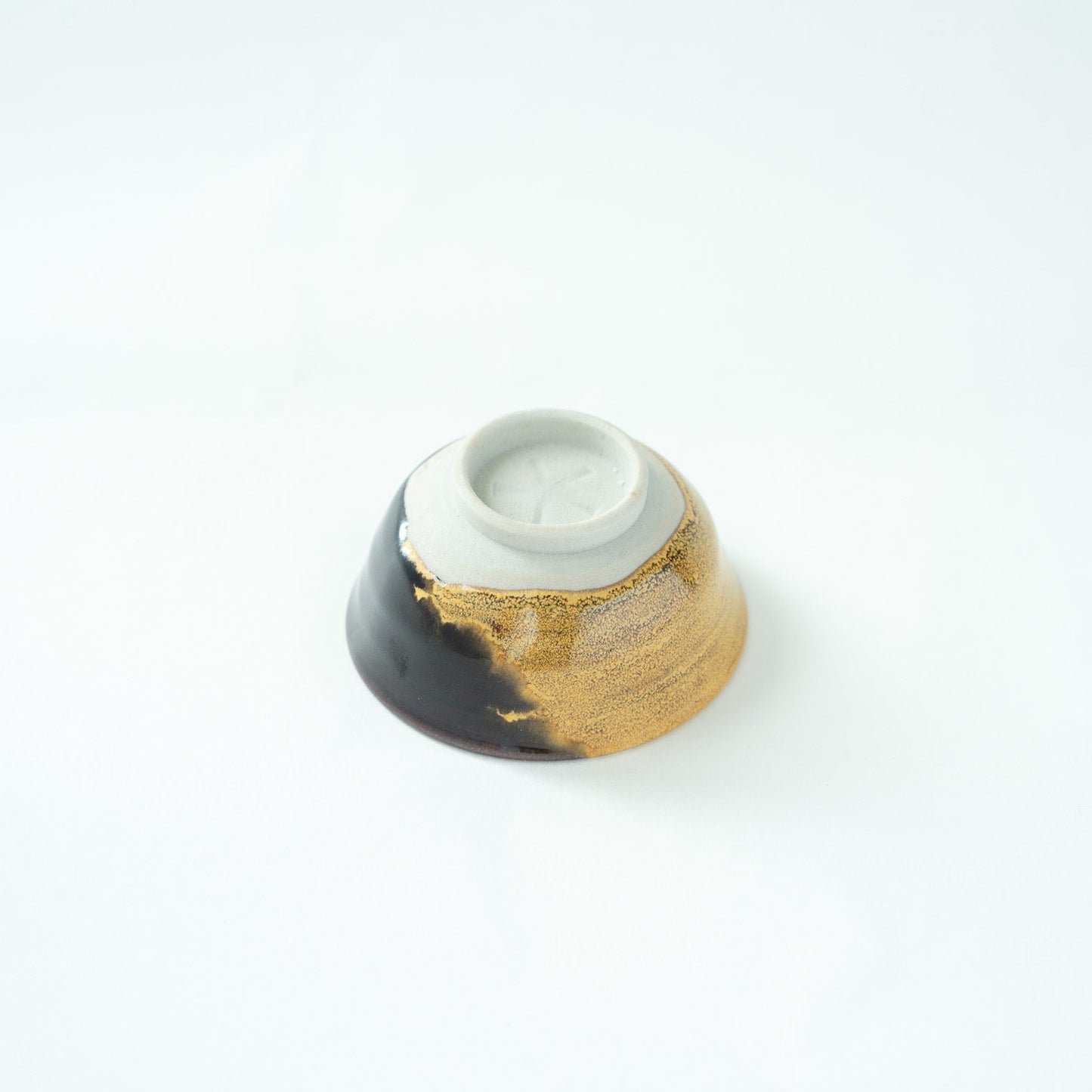 Inverted view of the GUINOMI, showcasing the finely trimmed, unglazed ceramic foot and the glaze flow near the base.