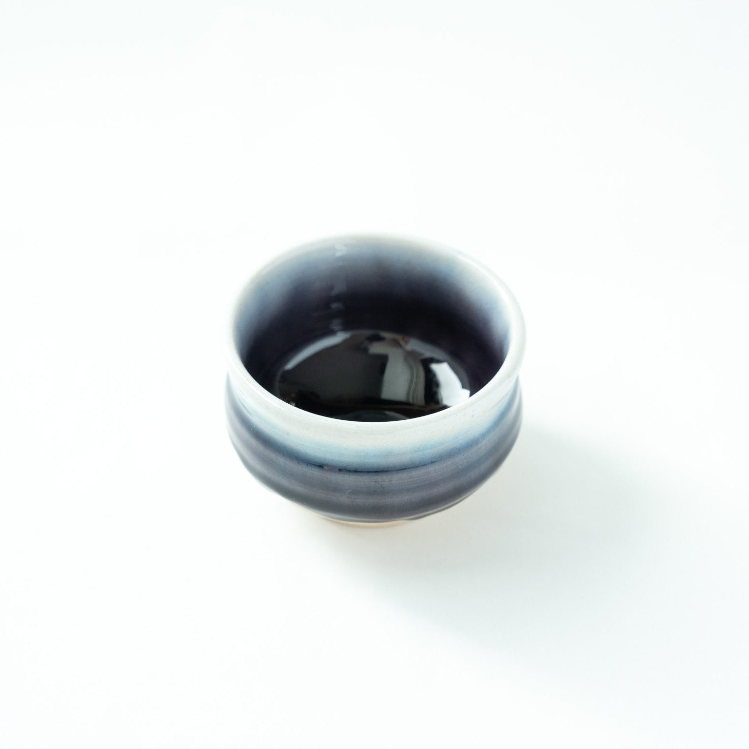 Top view of the vessel, revealing the intense depth of the glossy dark glaze inside balanced by a pale blue rim.