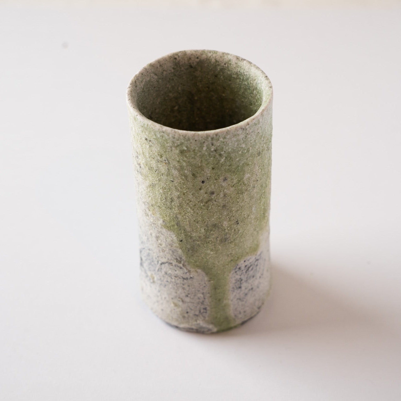 Top-down view of the front face of Yui Tsujimura’s cylindrical YUNOMI cup, highlighting the vertical path of the pale green natural ash glaze melt.