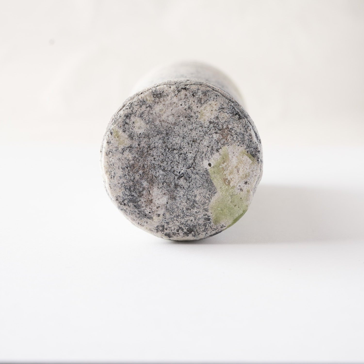 Looking directly into the deep interior of Yui Tsujimura's cylindrical YUNOMI cup, revealing dark grey clay tones and a subtle pool of green at the inner base.