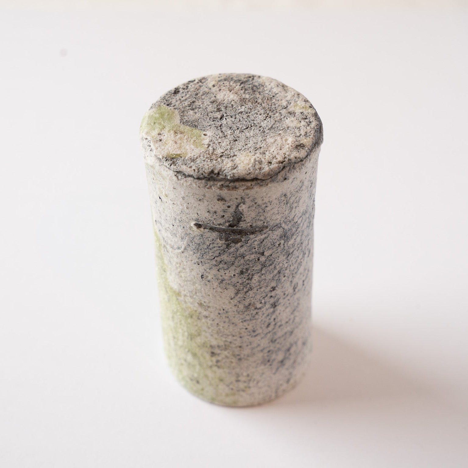 An upside-down view of the tall YUNOMI cup by Yui Tsujimura, displaying the flat base and the crisp profile of the incised signature mark on the side.