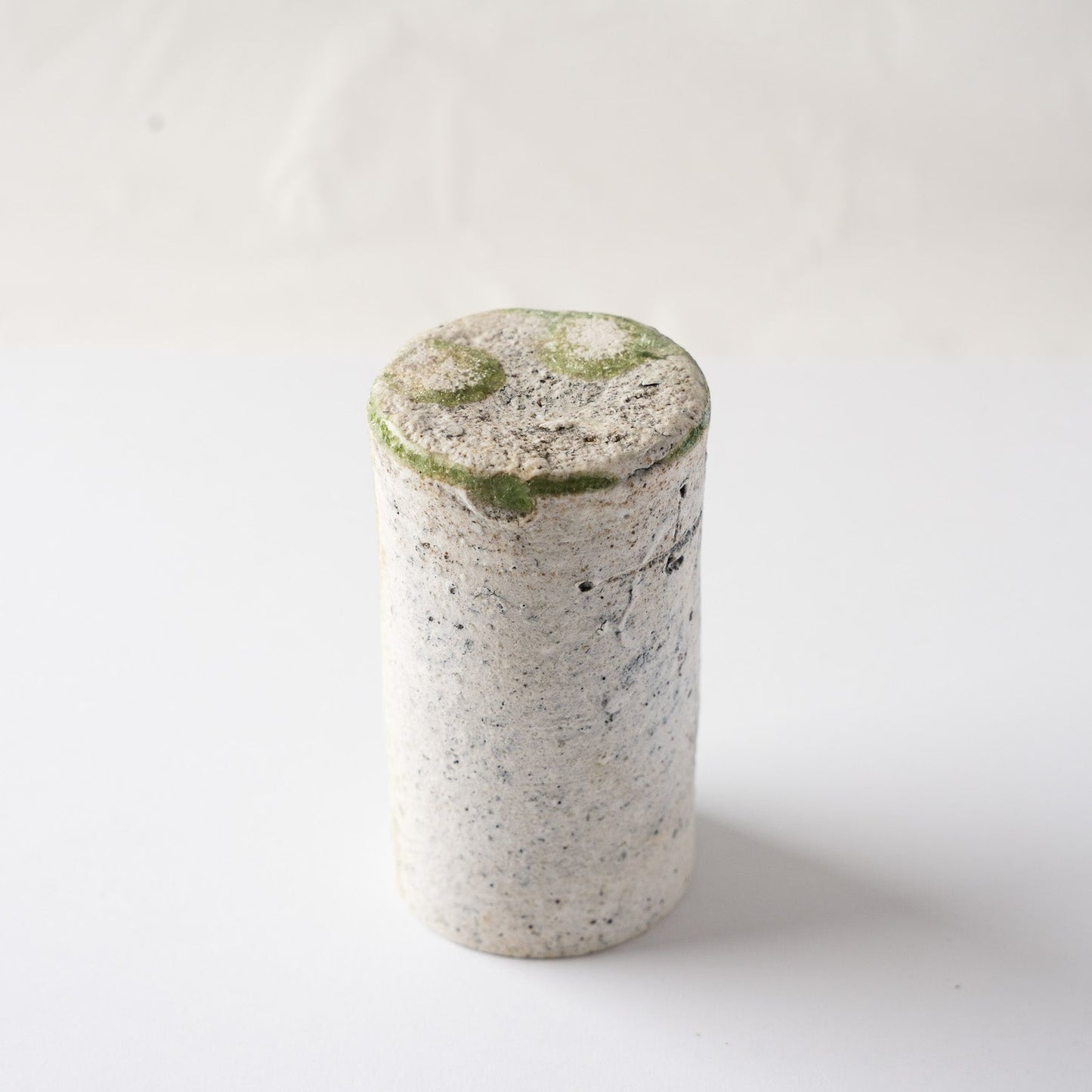 Inverted view of the cylindrical natural ash glaze YUNOMI cup by Yui Tsujimura, detailing the contrast between the white textured body and the green base crystals.