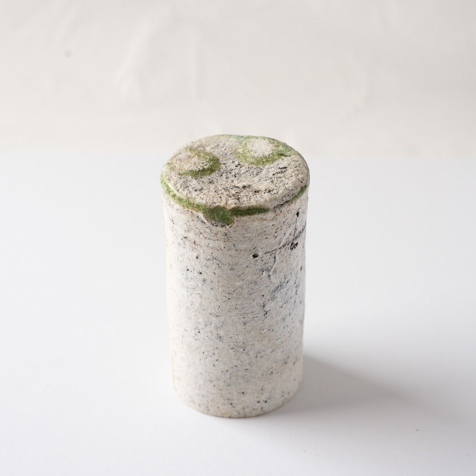 Inverted view of the cylindrical natural ash glaze YUNOMI cup by Yui Tsujimura, detailing the contrast between the white textured body and the green base crystals.