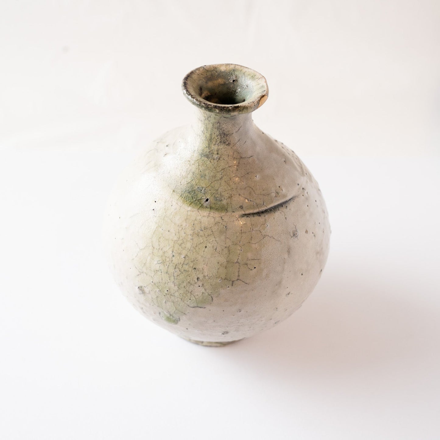 High-angle perspective showing the fine crackle glaze network and pale green natural vidro melt on the TOKKURI flask by Yui Tsujimura.