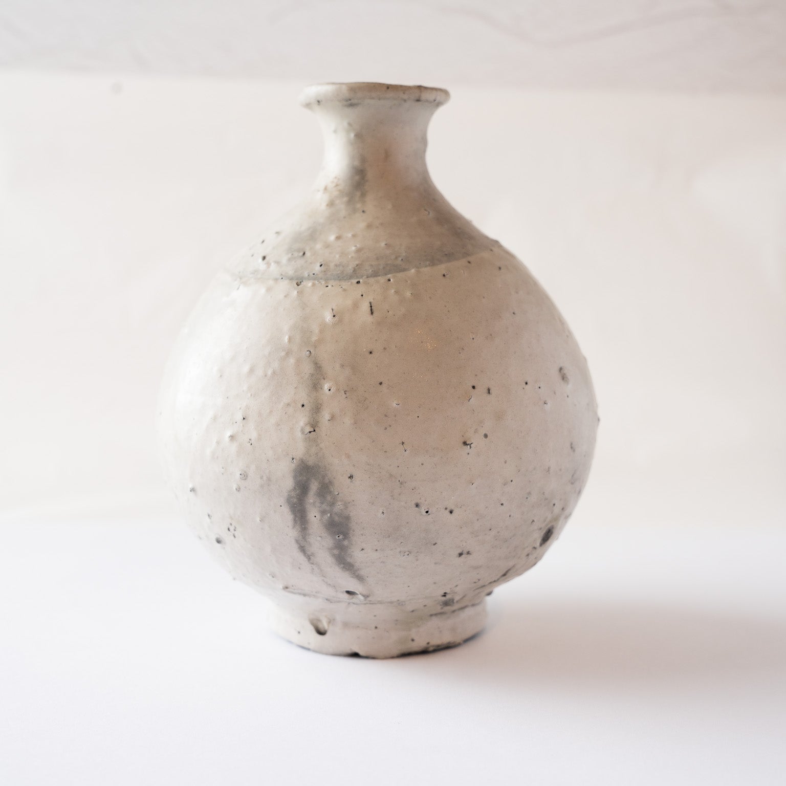 Profile view of the natural ash glaze TOKKURI by Yui Tsujimura, displaying a dark charcoal kiln marking across the lower rounded surface.