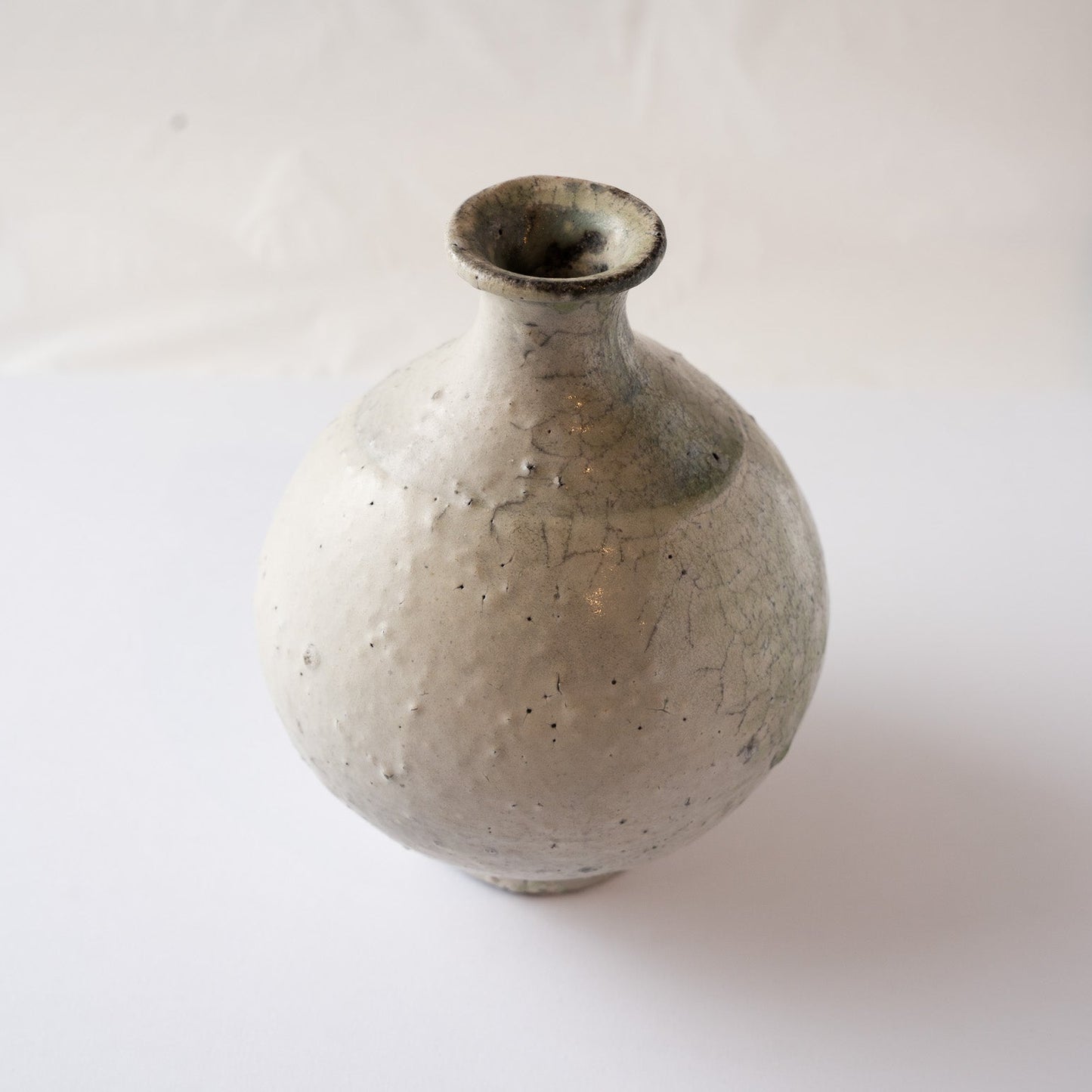 High-angle view of Yui Tsujimura’s spherical TOKKURI, highlighting the pale green ash glaze pooling on the shoulder.