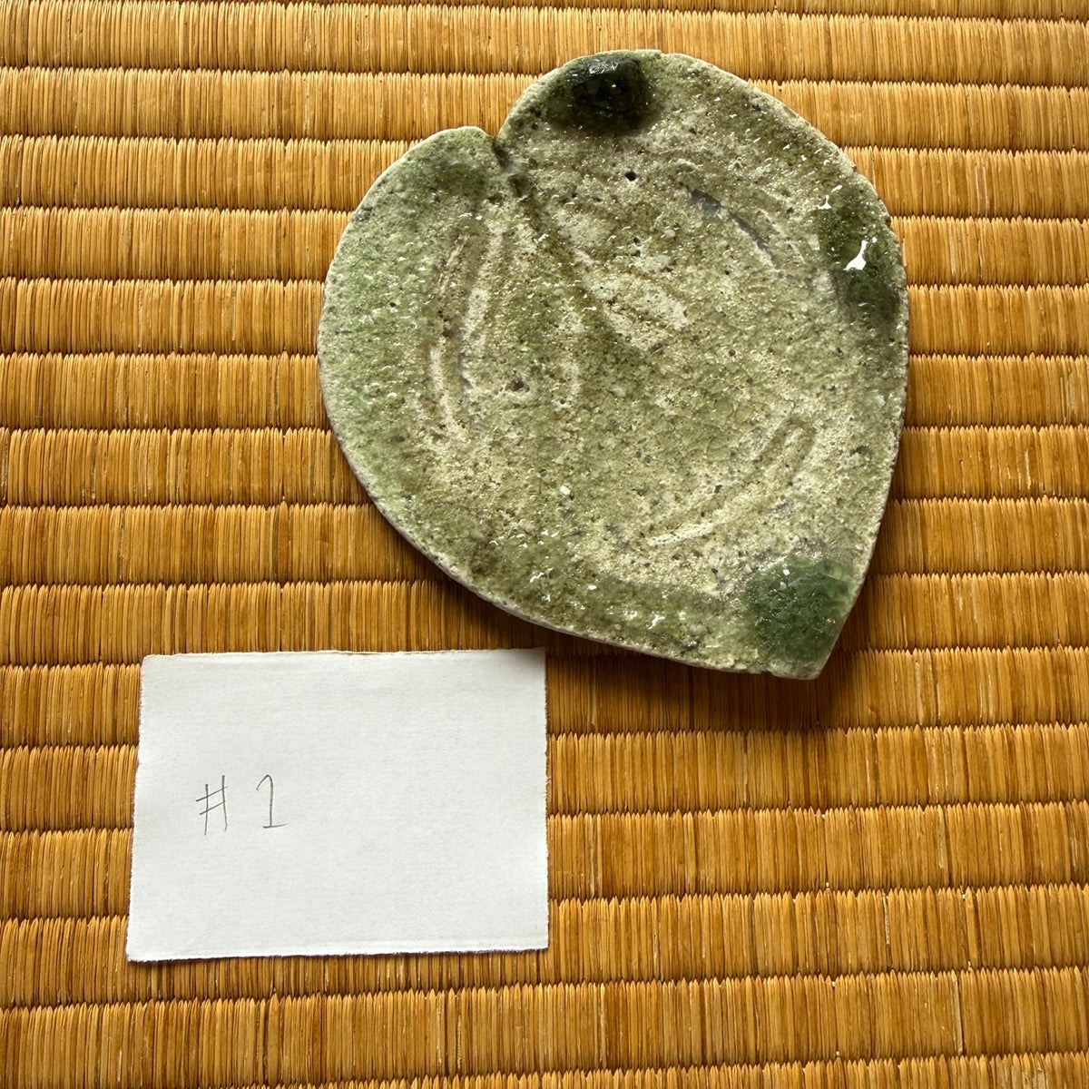 Top view of plate 1 from Yui Tsujimura’s natural ash glaze viburnum leaf dish set, showing incised vein patterns and a thick deep-green vidro pool at the top cleft.