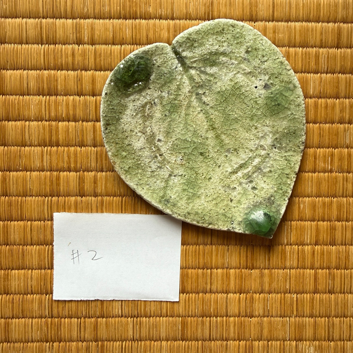 Top view of plate 2 from Yui Tsujimura’s natural ash glaze viburnum leaf dish set, featuring prominent leaf vein markings and twin emerald vidro droplets at the rim and tip.