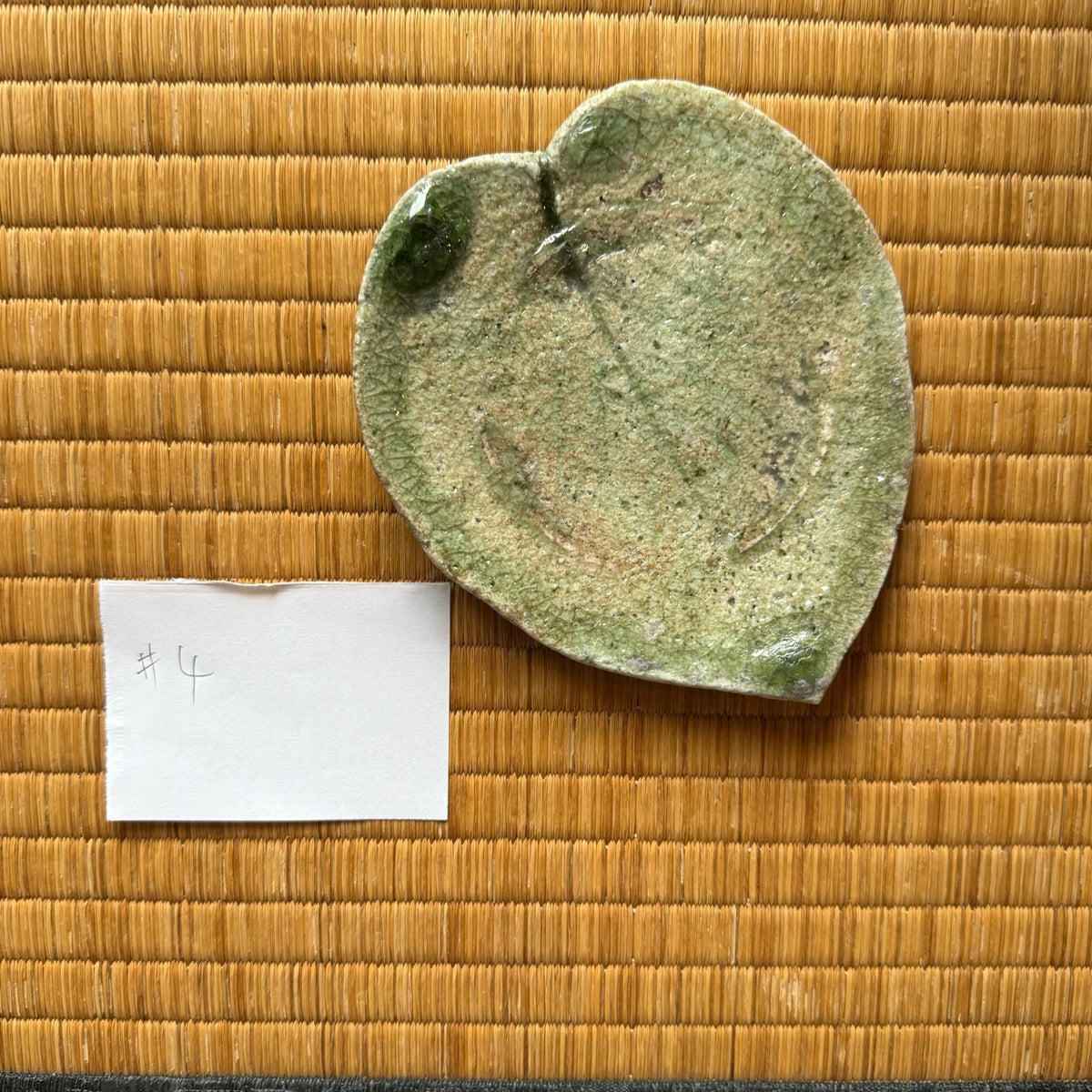 Top view of plate 4 from the natural ash glaze viburnum leaf dish set by Yui Tsujimura, highlighting an incised central vein and deep emerald vidro glaze pooling at the top rim.