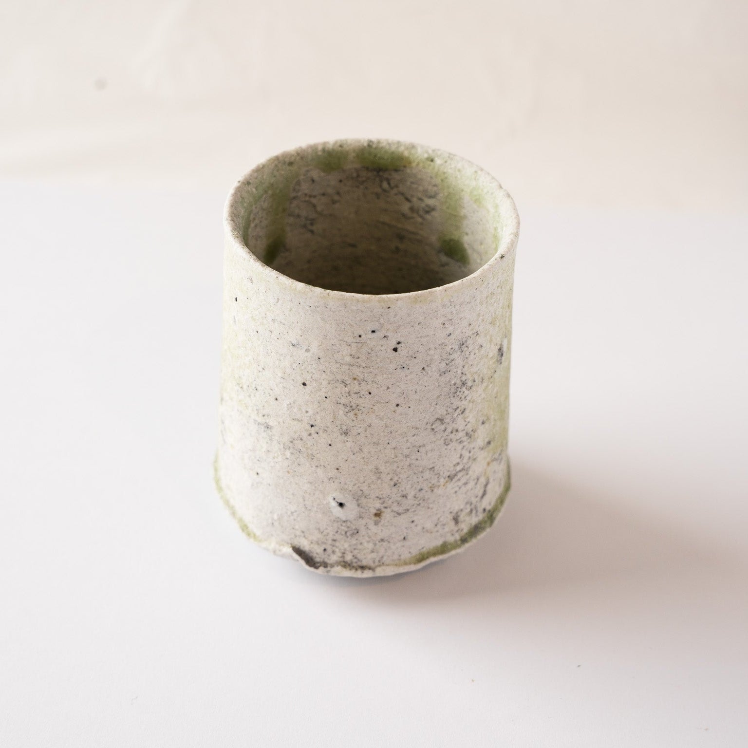 The reverse side of the natural ash glaze YUNOMI cup by Yui Tsujimura, showcasing the minimalist, pale rustic ceramic texture with subtle iron spots.
