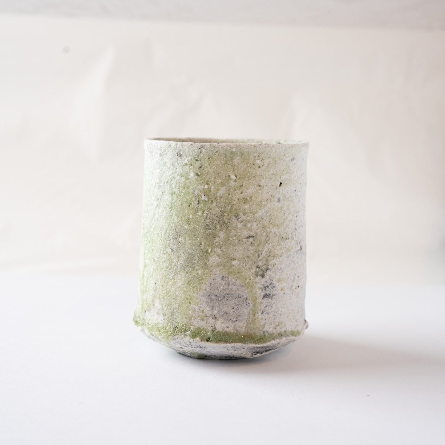 Eye-level view of the Yui Tsujimura YUNOMI cup, presenting the quiet radiance and earthy strength of the natural vidro glaze pooling at the base.