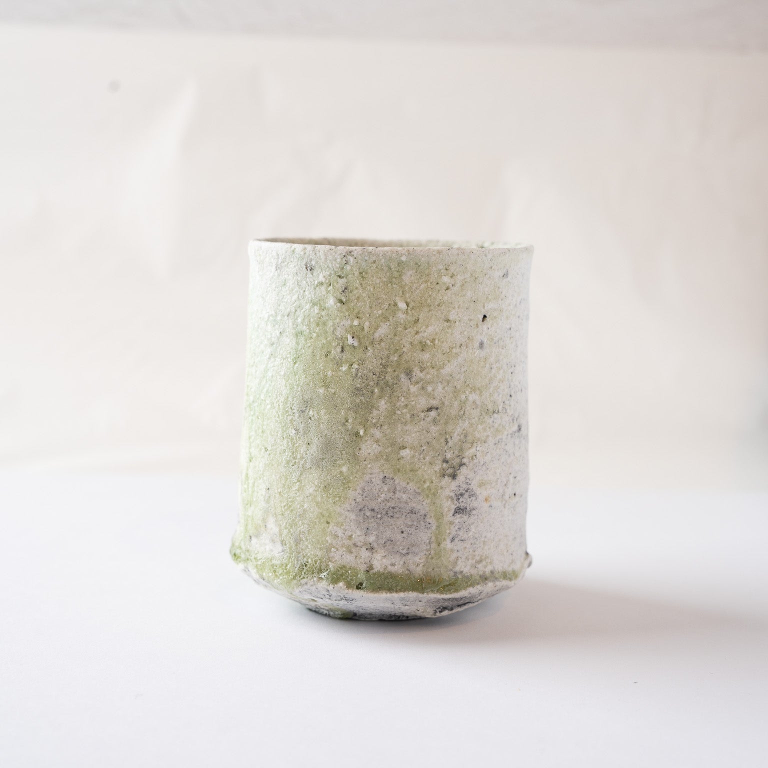 Eye-level view of the Yui Tsujimura YUNOMI cup, presenting the quiet radiance and earthy strength of the natural vidro glaze pooling at the base.