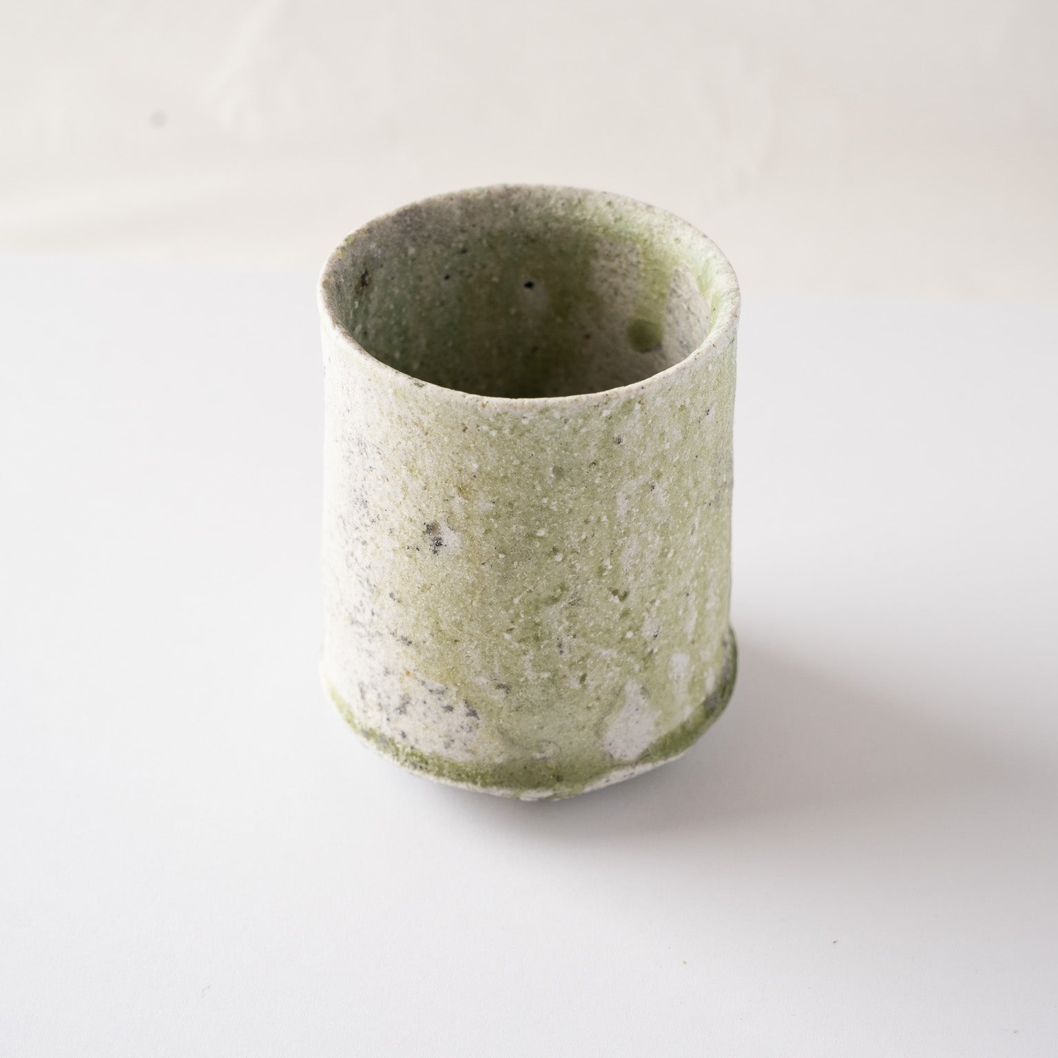 Front view of the YUNOMI tea cup by Yui Tsujimura, illustrating the elegant asymmetry and serene green color transitions formed through kiln transformation.