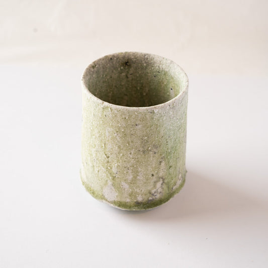 High-angle view of a natural ash glaze YUNOMI cup by Yui Tsujimura, showing the pale green vidro glaze pooling near the base against a clean background.
