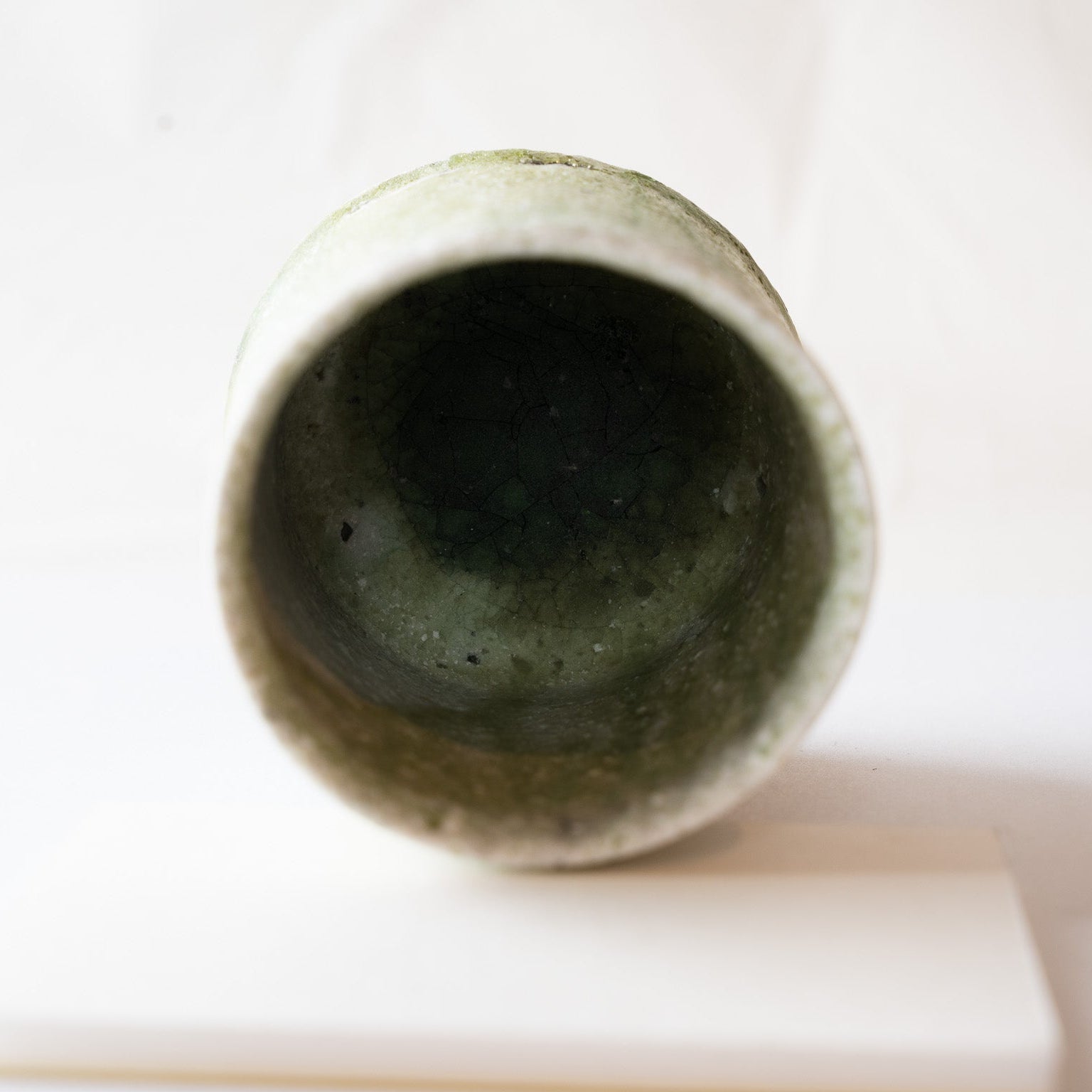 Close-up interior view looking down into a natural ash glaze YUNOMI cup by Yui Tsujimura, showcasing a thick, deep moss-green vidro pool with fine crackle lines.