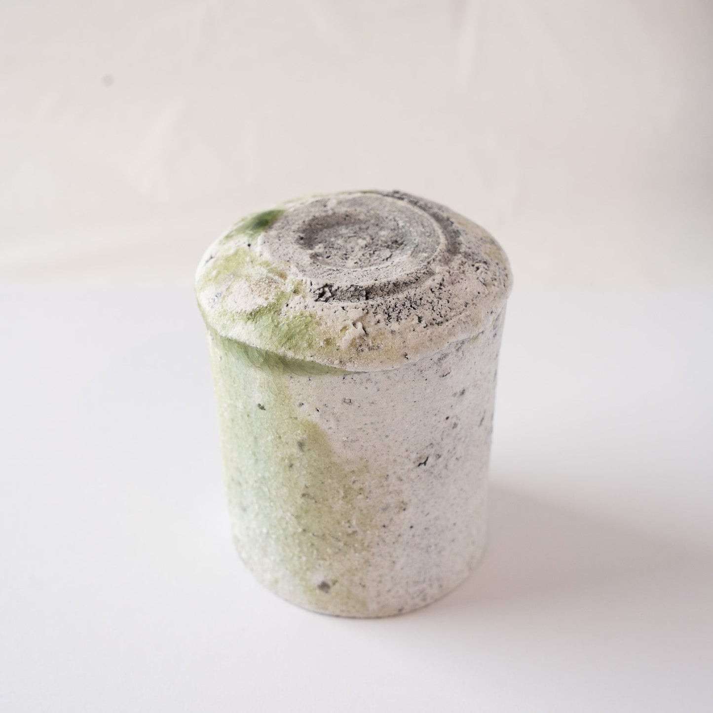 Upside-down view of the natural ash glaze YUNOMI cup by Yui Tsujimura, detailing the dramatic flow of natural glaze and the thick vidro melt at the bottom edge.