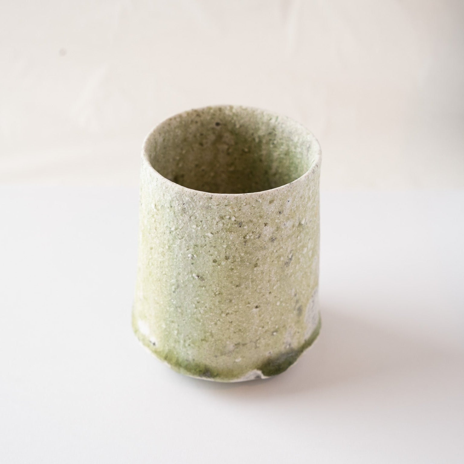 Three-quarter view of the natural ash glaze YUNOMI by Yui Tsujimura, balancing the visibility of the soft green exterior and the deep pooled interior.