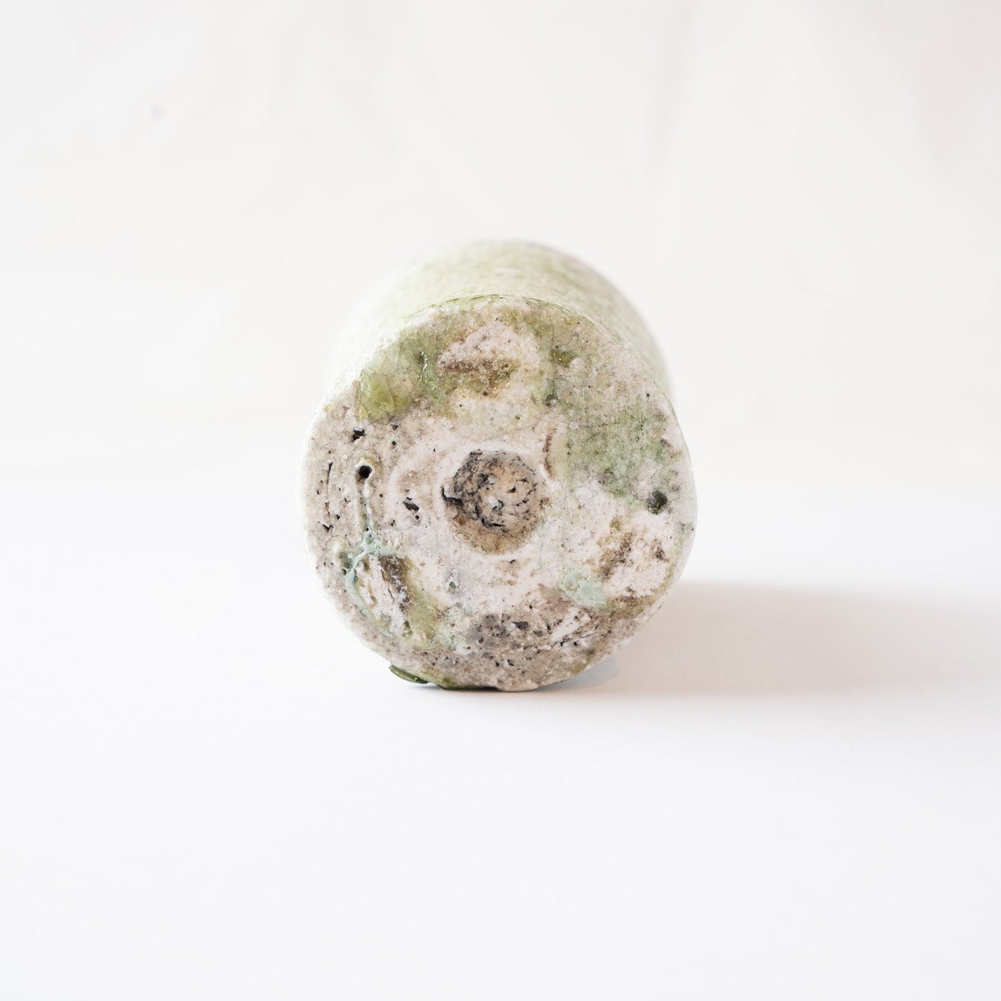 Underneath view of the flat, circular carved base of the YUNOMI cup, showing light green ash glaze rings and a rough gray central clay core.