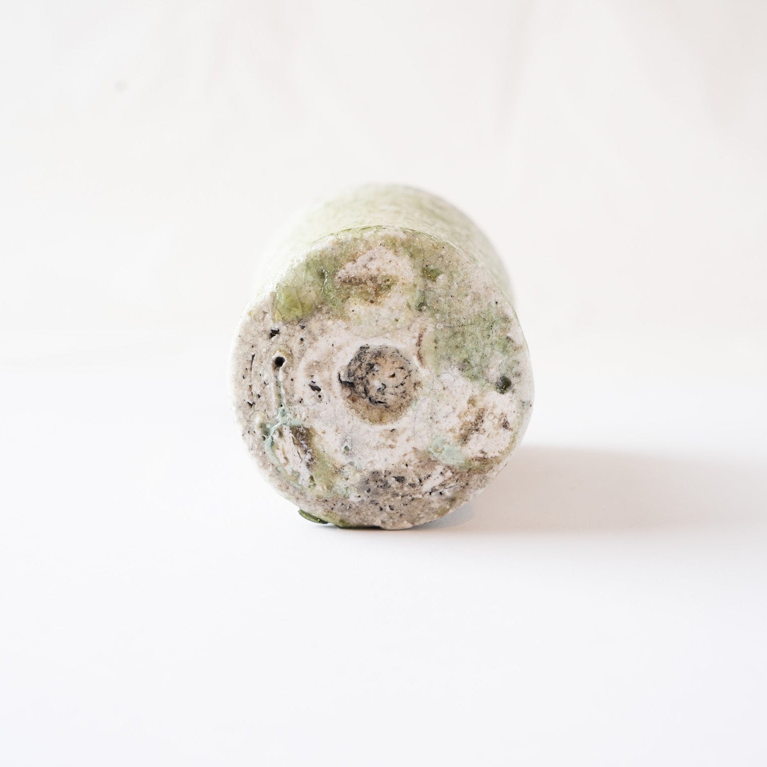 Underneath view of the flat, circular carved base of the YUNOMI cup, showing light green ash glaze rings and a rough gray central clay core.