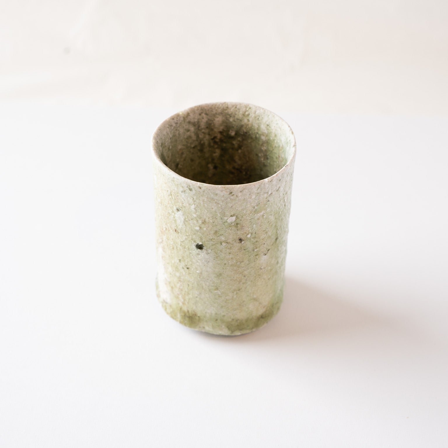 High-angle perspective from the white ash-textured side of the cylinder ceramic cup, showing the subtle irregularities of the rim.
