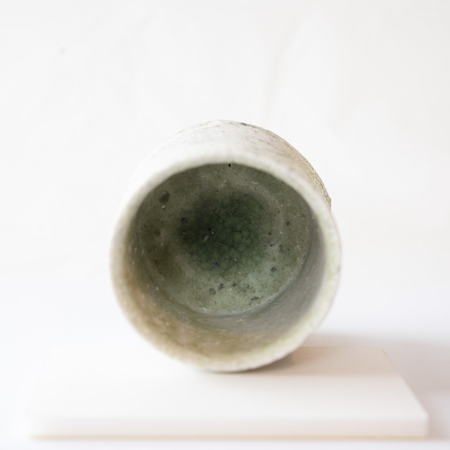 Top-down look into the interior of the YUNOMI cup, revealing a pool of glassy emerald green glaze with delicate crackle lines at the base.