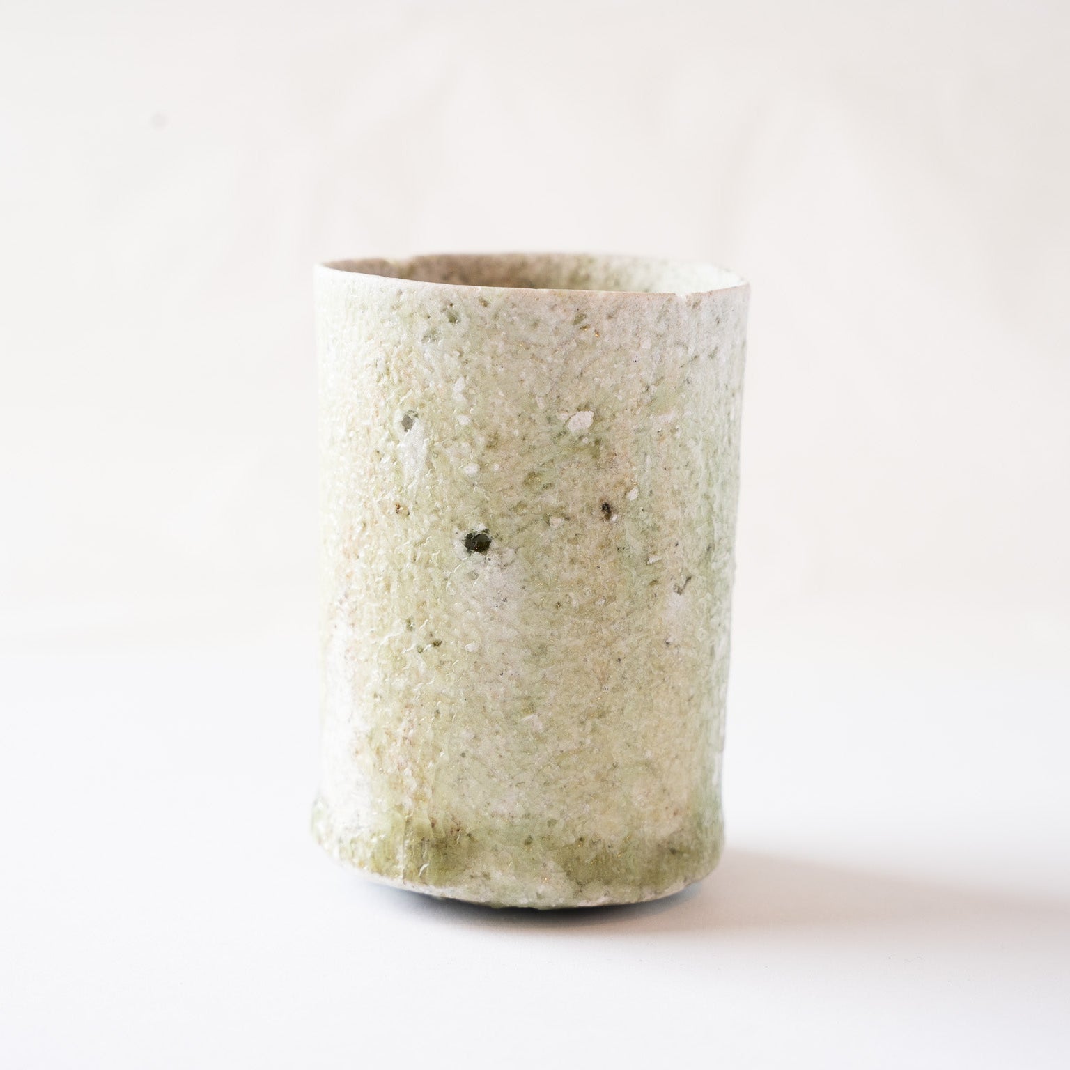 View centered on the reverse side of the YUNOMI cup, showing a uniform pale moss green and white crystalline ash texture with a single small dark fusion spot.