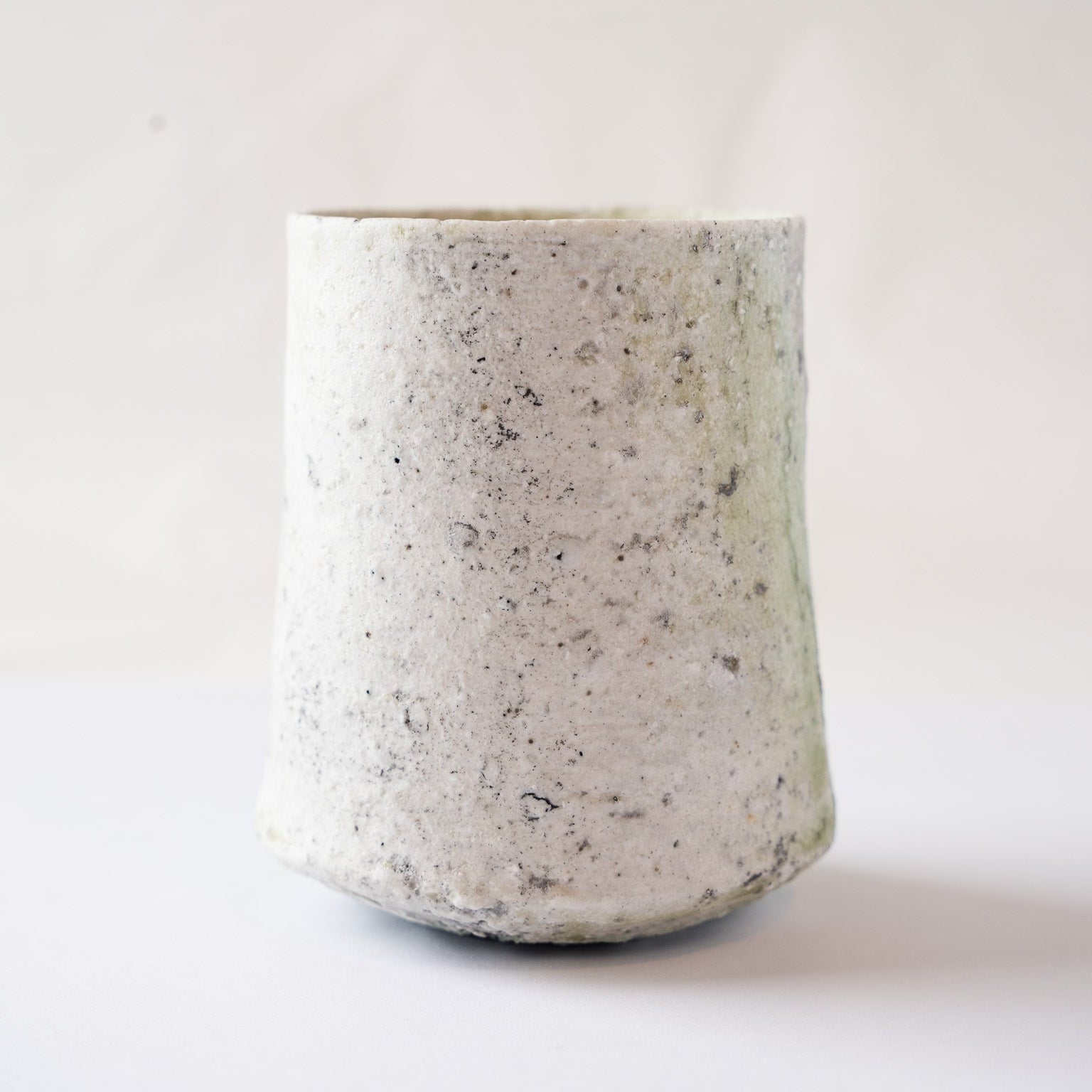 Side profile view of the white crystalline ash side of the ceramic YUNOMI cup, illustrating its subtly irregular cylinder silhouette.