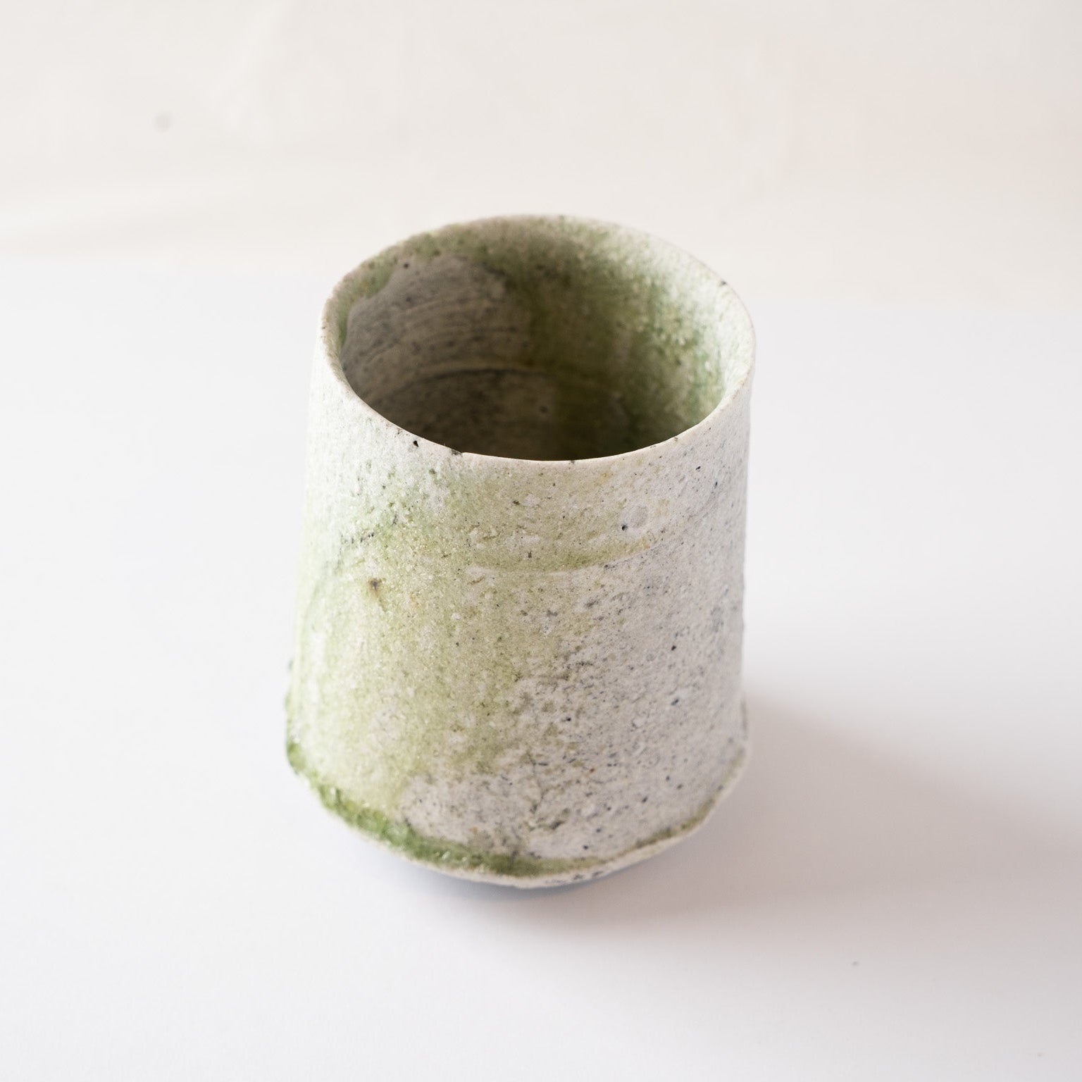 High-angle perspective of the natural glaze YUNOMI cup by Yui Tsujimura, showcasing the rich multi-layered texture and organic rim shape under natural light.